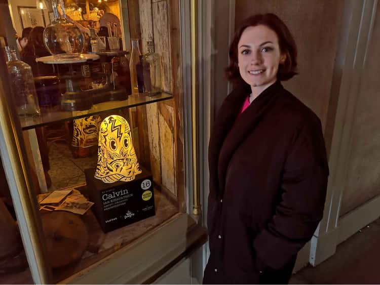 Naomi stood next to a shop window displaying a large lit up figure of a ghost for the York Ghost Hunt.