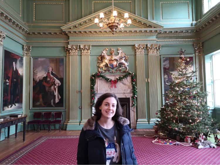 Naomi in the foreground, with a christmas tree, festive decorations amongst the traditional portraits and historic green walls of the Mansion House in York.