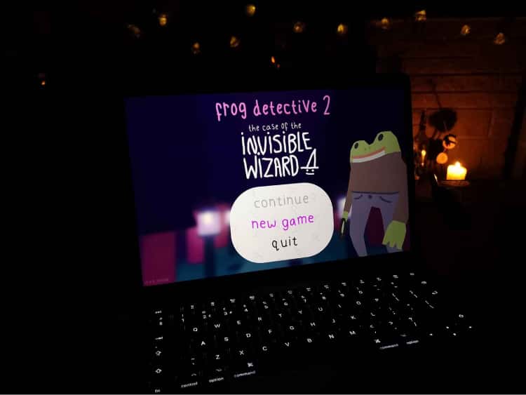 A picture of my laptop with the menu of Frog Detective 2 on the screen. The menu displays the frog detective, the title of the game, Frog Detective 2: The Case of the Invisible Wizard and the option to start a new game highlighted.