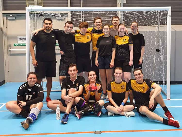 Myself with the University of York handball team, 13 of us in total, in two rows, smiling for the camera in front of one of the handball goals, following our 2nd game of the season.