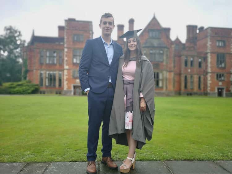 Myself (dressed in a blue suit) and Naomi (in a pink dress and graduation robes) in front of the University of York's Heslington Hall