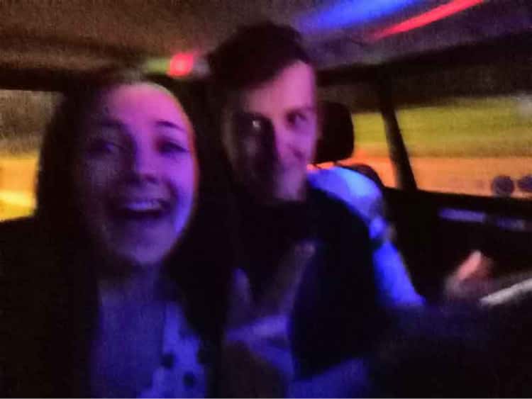 Myself and Naomi in the back of a taxi, covered in bright multi-coloured lights, posing awkwardly so that the taxi driver does not see us.